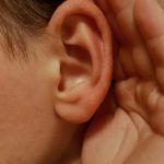 A person cupping their ear to listen closely